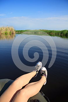 Feet girl in sneakers on the river landscape