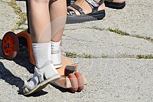 Feet girls close-up on a scooter. Child riding scooter. Safety ride on a children`s scooter