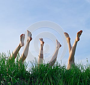 Feet of girls laying and sunbathing in a grass