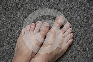 Feet on a gray home carpet, female feet without shoes