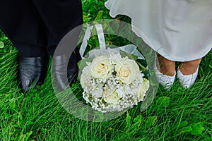 Feet of groom and bride with wedding bouquet