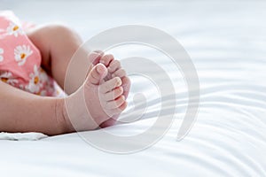 Feet of a half Thai half Nigerian baby newborn girl is 1-month-old, lying on a white bed