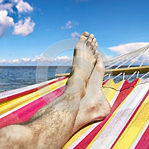 Feet in the hammock against the sea