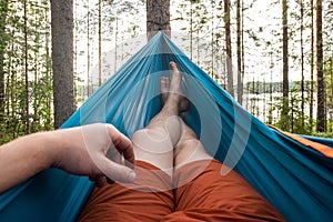 Feet in the hammock on a background of pine forest