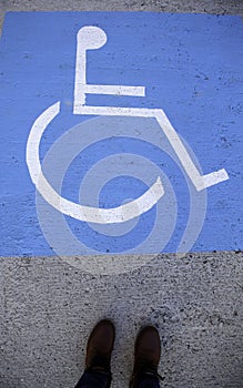 Feet on a handicapped sign on the asphalt