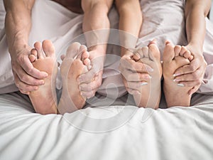 Feet and hands of a young couple that lying on the bed at honeymoon. Couple in love. Concept : love, sweetheart, sweet