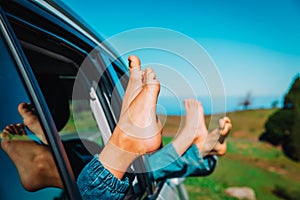 Feet of happy kids travel by car in nature