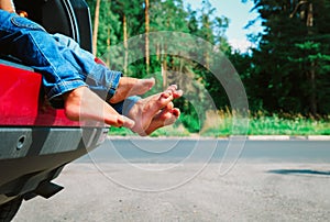 Feet of happy kids travel by car in summer nature