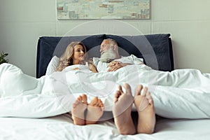 Feet of happy mature couple resting together in bed