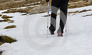 FEET OF A HIKER WALKING WITH POLES THROUGH THE SNOW photo