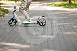 Feet of a kid boy with scooter on a sunny day. child outdoors, active sport kids