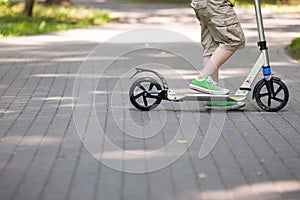 Feet of a kid boy with scooter on a sunny day. child outdoors, active sport kids