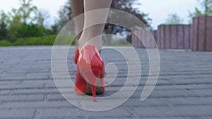 Feet of lady walking street in red high heel shoes alone, risk of attack, danger