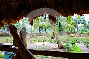 Feet leaning against a fence in a jungle hut