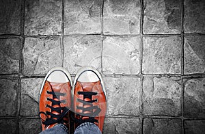 Feet in leather sneaker on pavement background