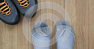 Feet with Left and Right grey socks move toes, next to hiking shoes, on wooden floor