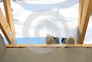 Feet and legs of builders working on a roof