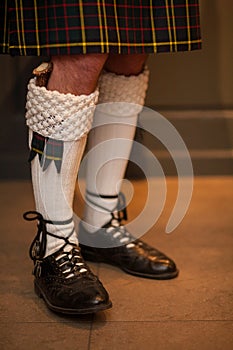 Feet and legs in Scottish skirts, a Scottish traditionally dressed bagpiper plays on St. Patrick& x27;s Day, holiday costumes