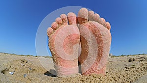 Feet legs strewn sprinkled with sand sanded on the sandy beach.