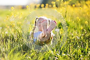 Feet of little girl in yellow field with flowers