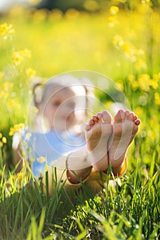 Feet of little girl in yellow field with flowers