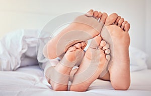 Feet, love and a couple in bed to relax in the morning while bonding in their home for trust or support. Bedroom