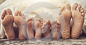 Feet, love and family in bed together to relax on a weekend morning in their home with flare. Mother, father and