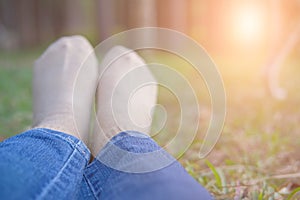 feet lying resting on grass in pine tree forest. leg wearing jeans relaxing in park