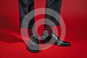 Feet of man in business pants and shoes with funny red and black striped socks