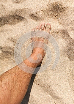 Feet of a man in the hot sand of the desert