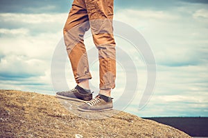Feet man standing on rocky mountain outdoor