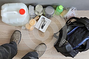 Feet of man, tank with water and long-term storage products, bags with things