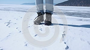 The feet of a man in trekking boots jump and trample in the snow. Close-up.