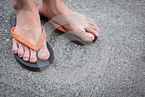 Feet of a man wearing sandals on concrete floor.