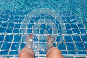 Feet of man who is sitting on the tile stairs