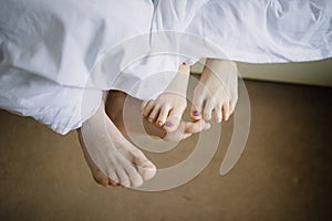 Feet of man and woman in bed close-up
