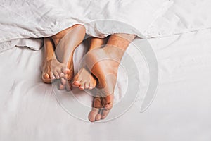 Feet of man and woman having sex in a bed