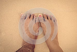 feet of men and women in the sea sand