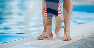 Feet of mother and child by the pool