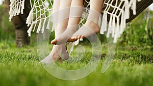 Feet of mother and child, swinging on hammock at summer. Relax, happy childhood