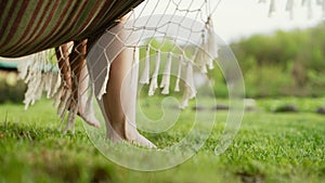 Feet of mother and child, swinging on hammock at summer. Relax, happy childhood