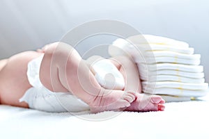 Feet of newborn baby on changing table with diapers