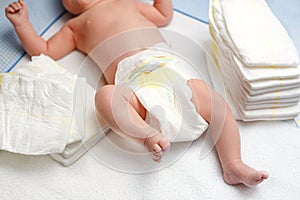 Feet of newborn baby on changing table with diapers. Cute little girl or boy two weeks old. Dry and healthy body and