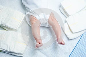 Feet of newborn baby on changing table with diapers. Cute little girl or boy two weeks old. Dry and healthy body and