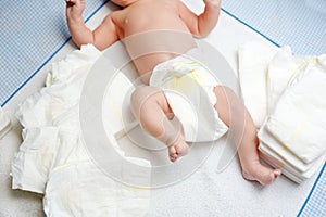 Feet of newborn baby on changing table with diapers. Cute little girl or boy two weeks old. Dry and healthy body and