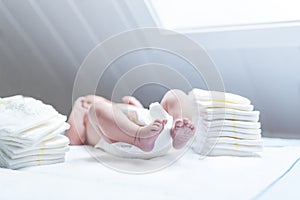 Feet of newborn baby on changing table with diapers