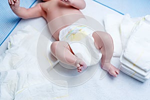 Feet of newborn baby on changing table with diapers