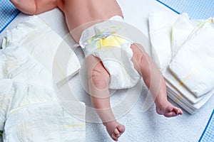 Feet of newborn baby on changing table with diapers