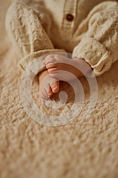 feet of a newborn, the baby is dressed in a warm knitted suit