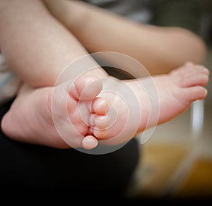 Feet of newborn baby in the hand of mother